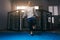 Sportsman in grey hoodie exercises with jump rope near boxing ring.