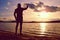 Sportsman holding cellphone and taking picture of autumn sunset or sunrise in picturesque sea scenery. End of season at resort.