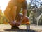 Sportsman laces his sneakers sitting and looking forward. Blurred background with forest, kids playground and football goal