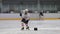 Sportsman leads puck with stick skating along large ice rink