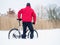 Sportsman with mountain bike lost in snow. Winter in the field.
