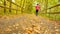 Sportsman in pink and black sportswear run on road. The man is slowly running on asphalt way covered by autumn leaves. Pathway