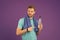 Sportsman point finger at plastic bottle on violet background. Man hold water bottle. Athlete in blue tshirt and shorts