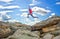 Sportsman running, jumping over rocks in mountain area.