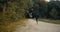 Sportsman running to a forest road opening. Drone back view. Motivated determined athlete on fall cross country path.