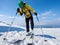 Sportsman skier on skis on snowy valley on background of bright blue sky and highland landscape.