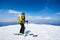 Sportsman skier on skis on snowy valley on background of bright blue sky and highland landscape.