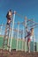 Sportsman and sportswoman at monkey bars. Sport couple training in metal jungle gym. Man athlete climb on top and woman