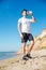 Sportsman standing and drinking water on the beach