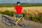 Sportsman standing next to bicycle. Wearing sports gear, helmet and glasses. Natural background.