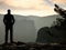 Sportsman is standing on the peak of sandstone rock in rock empires park and watching over the misty and foggy morning valley