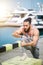 Sportsman with trendy hairstyle stretching body while standing at the sea pier