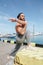 Sportsman with trendy hairstyle stretching body while standing at the sea pier