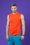 Sportsman on violet background. Muscular man in orange vest and blue shorts. Fit and confident. Sport fashion for