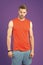 Sportsman on violet background. Muscular man in orange vest and blue shorts. Fit and confident. Sport fashion for