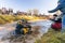 Sportsmen drive quad bikes splashing in deep water at Mud Racing contest. ATV SSV motobike