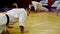 Sportsmen in kimonos perform push-ups on mat in spacious gym