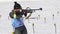 Sportswoman biathlete aiming, rifle shooting, reloading standing position. South Korea biathlete Lee Hyunju in shooting
