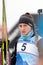 Sportswoman biathlete Knyazeva Elizaveta with skis in hands and rifle behind her