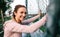 Sportswoman with boxer braids smiling leaning on a metal fence