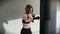 The sportswoman confidently strikes her hands in the boxing bag in the gym