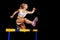 Sportswoman jumping over hurdle on sprint race