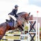 Sportswoman jumping over obstacles on competition