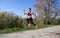 Sportswoman jumps while running along a trail in a natural environment