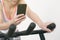 Sportswoman looking phone on spinning bike