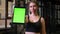 Sportswoman with ponytail shows tablet with chromakey green screen into camera being calm and positive in gym,