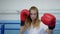 Sportswoman on ring makes accurate punches in boxing gloves and looking at camera on workout