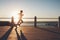 Sportswoman training on seaside promenade at sunset