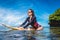 sportswoman in wetsuit and sunglasses on surfing board in ocean at Nusa dua Beach