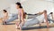 Sporty adult concentrated females and males doing stretching workout in pairs during group training