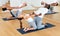 Sporty adult concentrated females and males doing stretching workout in pairs during group training