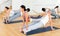 Sporty adult concentrated females and males doing stretching workout in pairs during group training