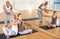 Sporty adult concentrated females and males doing stretching workout in pairs during group training