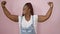 Sporty african american woman confidently flashing a strong arm gesture, smiling over a pink isolated background, emanating joy