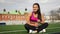 Sporty asian girl in sportswear is sitting on the stadium after training.