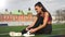 Sporty asian girl in sportswear is tying shoelaces on sneakers sitting on the stadium before training.