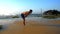 Sporty athlete stands on wet sandy beach with hands on knees