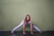 Sporty beautiful young brown-haired beginning yoga student woman in white sportswear doing Wide-Legged Forward Bend, Prasarita