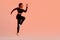 Sporty black lady jumping, having cardio training, wearing black fitwear, exercising over neon background, free space