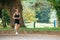 Sporty blonde runner woman running in park.