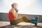 Sporty blonde skater sitting on ground and fastening helmet