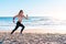 Sporty blonde woman running ocean beach. Young caucasian female exercising outdoors running seashore. Concept of healthy running