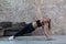 Sporty Caucasian girl doing side plank star exercise working abs and oblique muscles indoors against brick wall