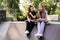 Sporty children girls with skateboard and penny boards are sitting and chatting with each other on sports ramp on