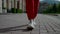 sporty dressed woman is walking in downtown in summer morning, closeup of feet, in sporty sneakers