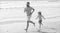 sporty family of daddy man and child boy running on beach together, summer